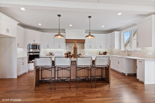 kitchen with white cabinetry, hanging light fixtures, stainless steel appliances, and a center island