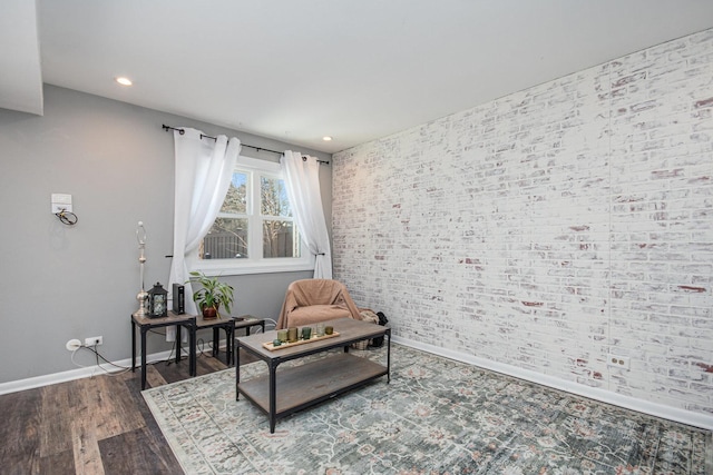 sitting room featuring brick wall, baseboards, wood finished floors, and recessed lighting