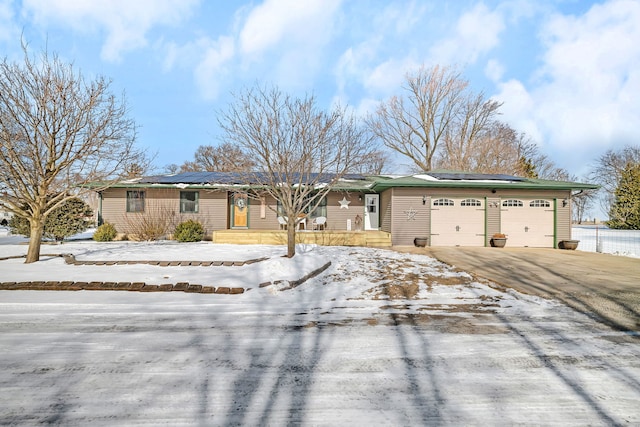 ranch-style home featuring driveway, an attached garage, and solar panels