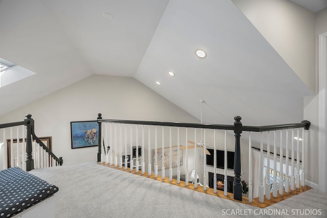 hallway featuring lofted ceiling with skylight, recessed lighting, and an upstairs landing