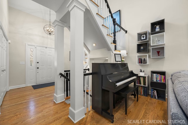 foyer featuring baseboards, a high ceiling, a chandelier, and wood finished floors