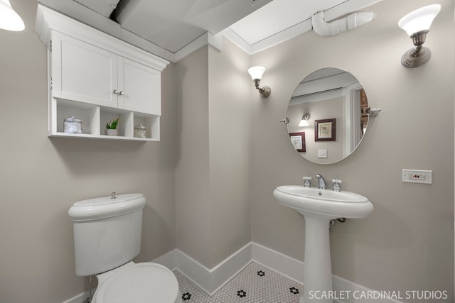 bathroom with tile patterned flooring, baseboards, a sink, and toilet