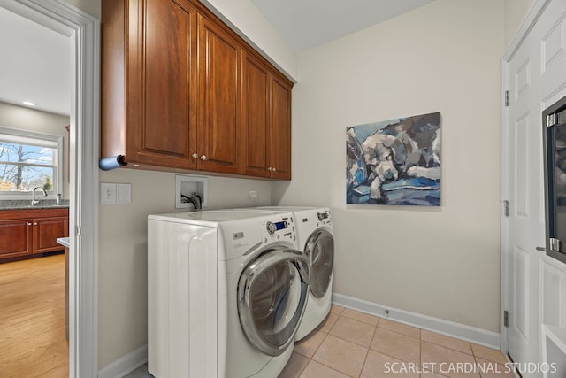 laundry room with light tile patterned floors, washing machine and dryer, a sink, baseboards, and cabinet space