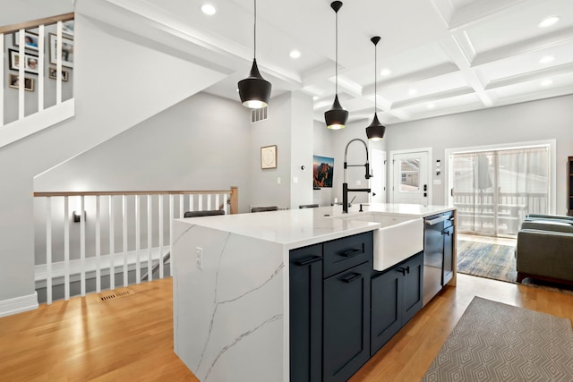 kitchen with dishwasher, hanging light fixtures, an island with sink, and light wood-style flooring