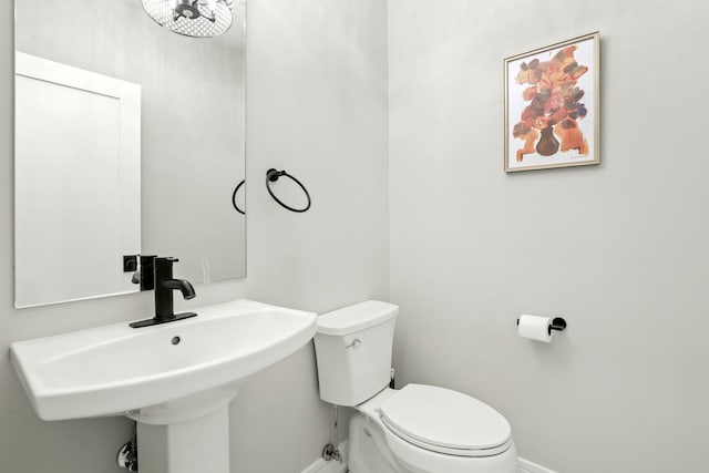 bathroom featuring toilet, baseboards, and a sink