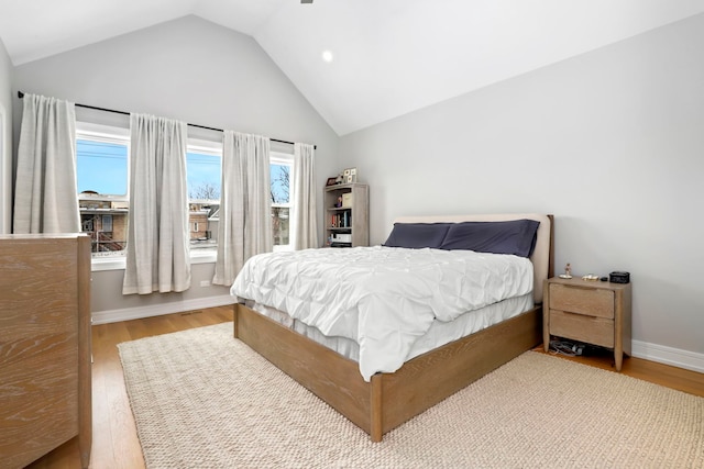 bedroom featuring vaulted ceiling, light wood-style flooring, and baseboards