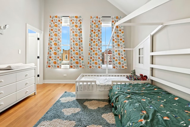 bedroom featuring lofted ceiling, light wood-type flooring, and baseboards