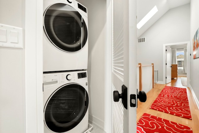 washroom with a skylight, laundry area, visible vents, light wood-style floors, and stacked washing maching and dryer