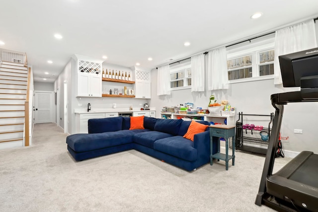 living room featuring recessed lighting, light colored carpet, wet bar, baseboards, and stairs