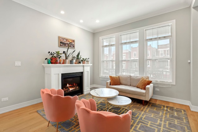 sitting room featuring ornamental molding, a glass covered fireplace, wood finished floors, and baseboards