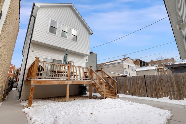 snow covered rear of property with central AC unit, stairs, fence, and a deck