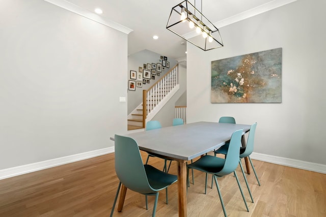 dining space with ornamental molding, light wood-type flooring, stairway, and baseboards