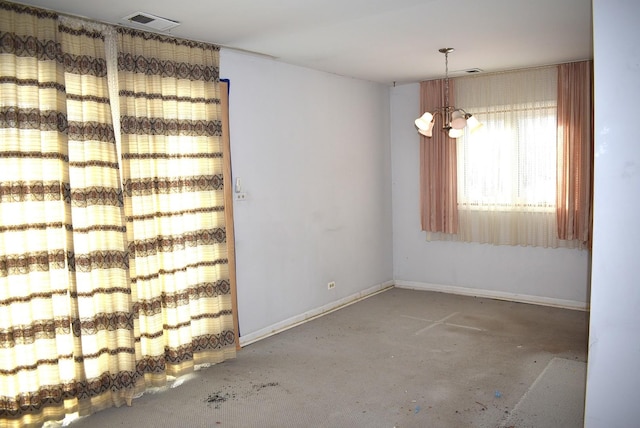 empty room with concrete flooring and a notable chandelier