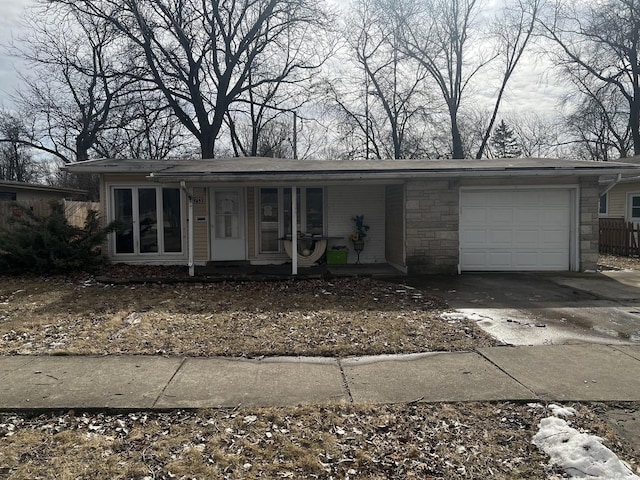 view of front of house with stone siding, covered porch, an attached garage, and concrete driveway