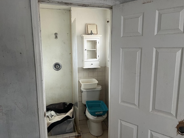 bathroom with toilet and tile walls