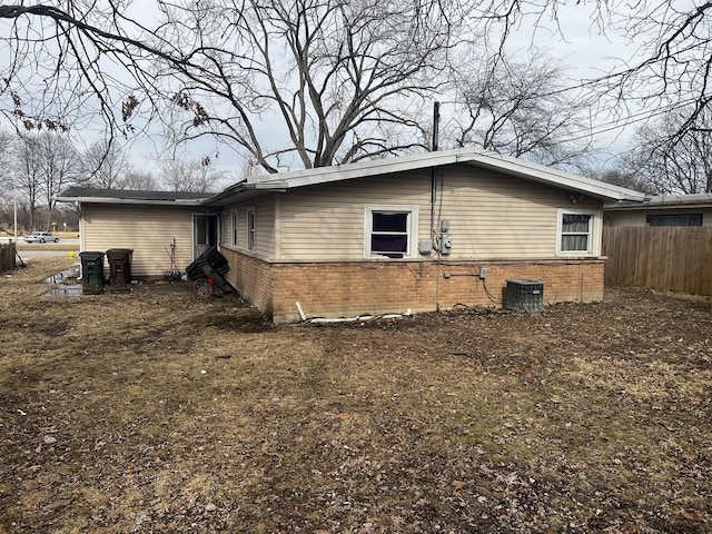 view of side of property featuring central air condition unit, fence, and brick siding