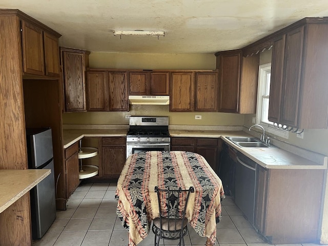 kitchen featuring appliances with stainless steel finishes, a sink, under cabinet range hood, and light tile patterned floors