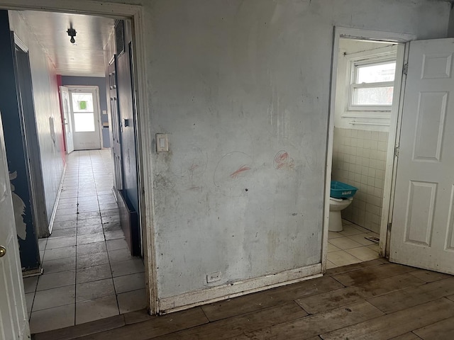 hall with wood-type flooring and tile walls