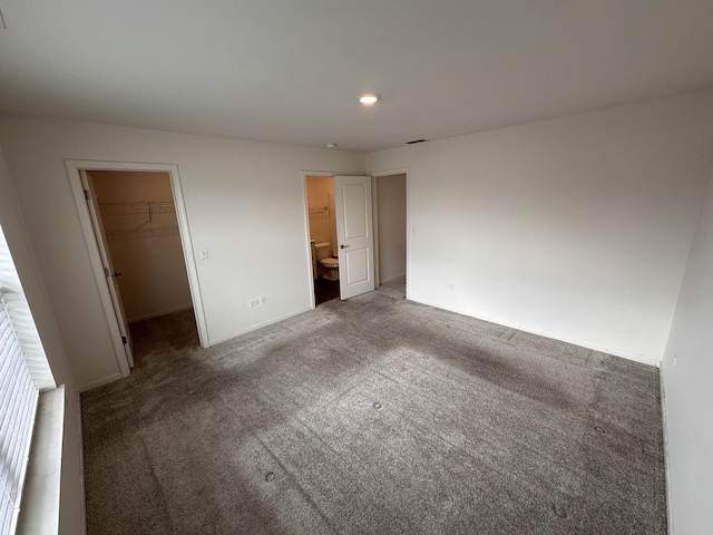 unfurnished bedroom with a closet, carpet flooring, and a walk in closet