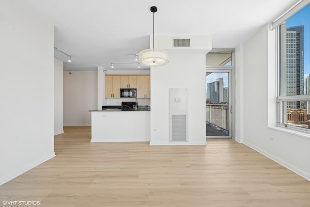 kitchen featuring black microwave, light brown cabinetry, dark countertops, and visible vents