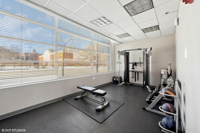 workout area with a paneled ceiling, baseboards, and visible vents