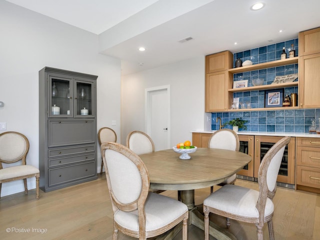 dining room featuring wine cooler and light hardwood / wood-style flooring