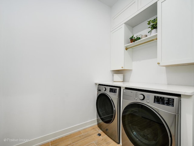 laundry room with light hardwood / wood-style flooring, independent washer and dryer, and cabinets