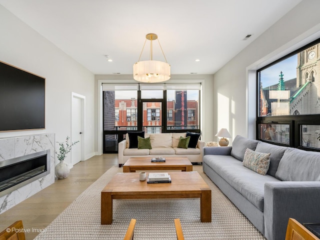 living room featuring a healthy amount of sunlight, a high end fireplace, and light hardwood / wood-style floors