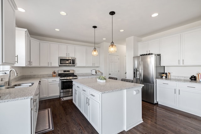 kitchen with stainless steel appliances, dark wood-style flooring, a sink, and a kitchen island