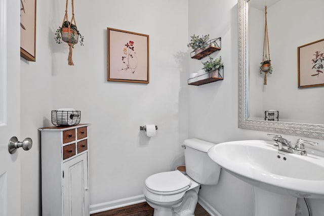 half bath with wood finished floors, a sink, toilet, and baseboards