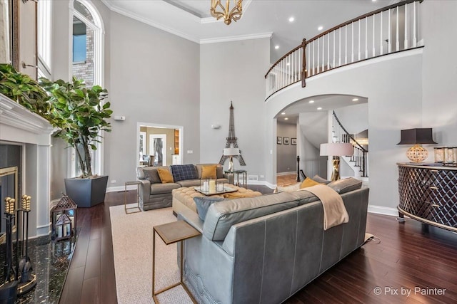 living room with stairs, ornamental molding, arched walkways, and dark wood-type flooring