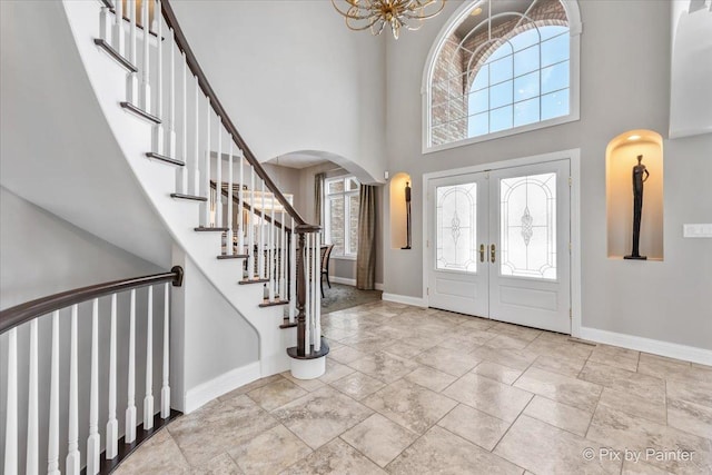 foyer entrance featuring french doors, a high ceiling, baseboards, and stairs