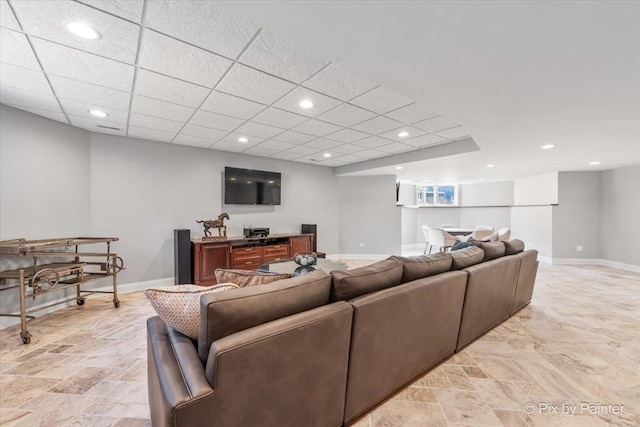 living area featuring a paneled ceiling, baseboards, and recessed lighting