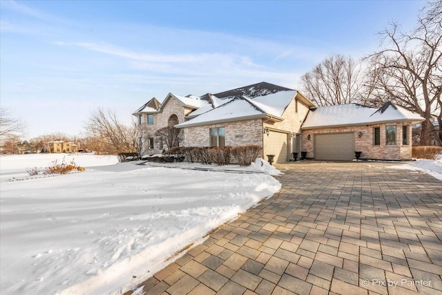 view of front of home featuring a garage, brick siding, and decorative driveway