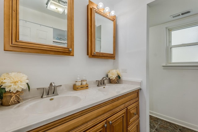 bathroom with double vanity, baseboards, visible vents, and a sink