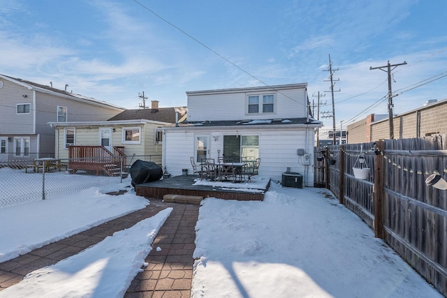 snow covered house featuring a fenced backyard, a deck, and central AC