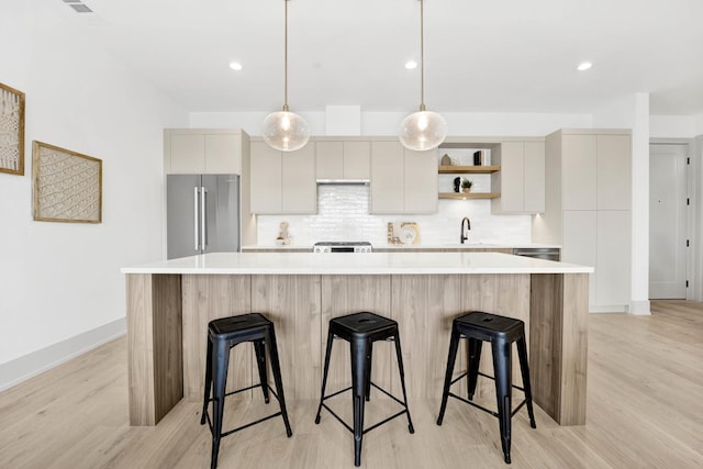 kitchen featuring a sink, high end fridge, light countertops, decorative backsplash, and open shelves