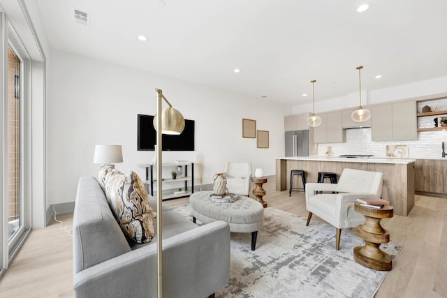 living area with recessed lighting, visible vents, and light wood finished floors