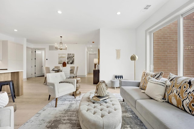 living room with recessed lighting, visible vents, light wood-style flooring, and an inviting chandelier