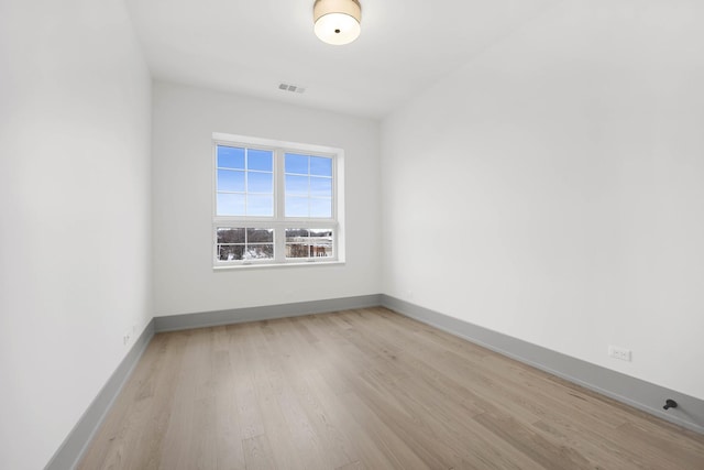 empty room featuring light wood-type flooring, baseboards, and visible vents