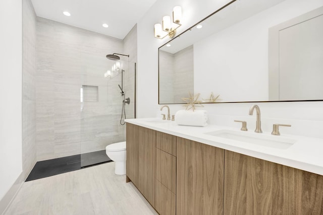 bathroom featuring double vanity, a sink, toilet, and a walk in shower