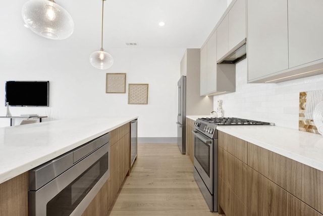 kitchen featuring under cabinet range hood, visible vents, modern cabinets, and appliances with stainless steel finishes