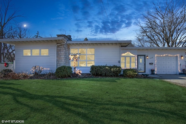 view of front of house with stone siding, a yard, a garage, and driveway