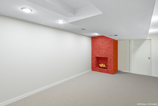 finished basement featuring a brick fireplace, carpet flooring, baseboards, and visible vents