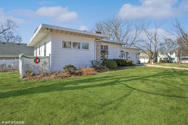 view of front of home with an attached garage, a chimney, a front yard, and fence