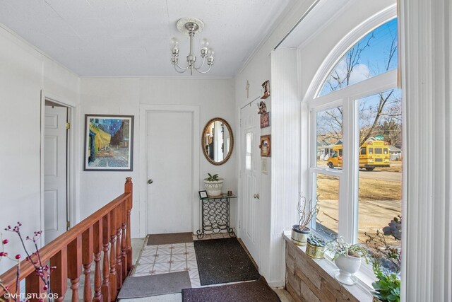 doorway featuring tile patterned floors, ornamental molding, and a chandelier