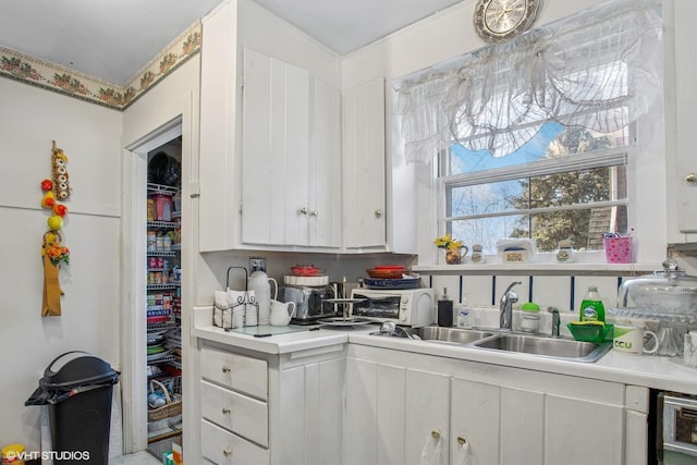 kitchen featuring light countertops, white cabinets, a toaster, and a sink