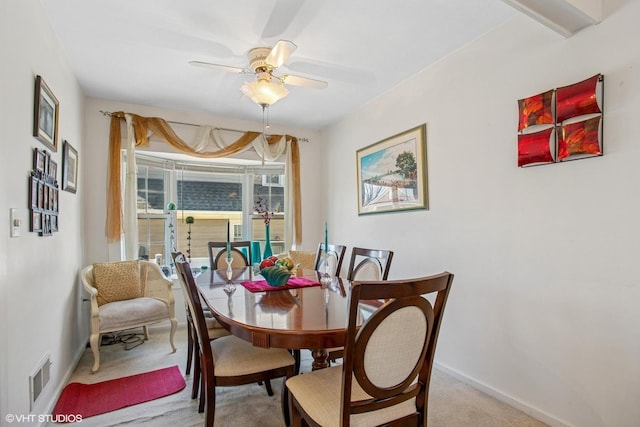 carpeted dining room featuring baseboards, visible vents, and ceiling fan