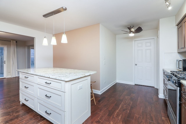 kitchen featuring light stone countertops, white cabinetry, appliances with stainless steel finishes, a center island, and decorative light fixtures