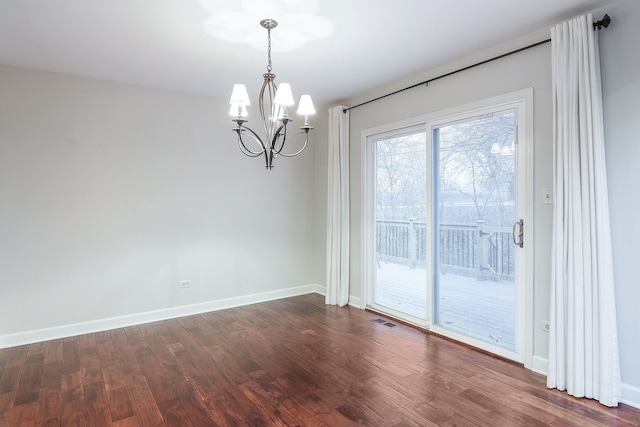 spare room with a chandelier, dark wood-type flooring, visible vents, and baseboards